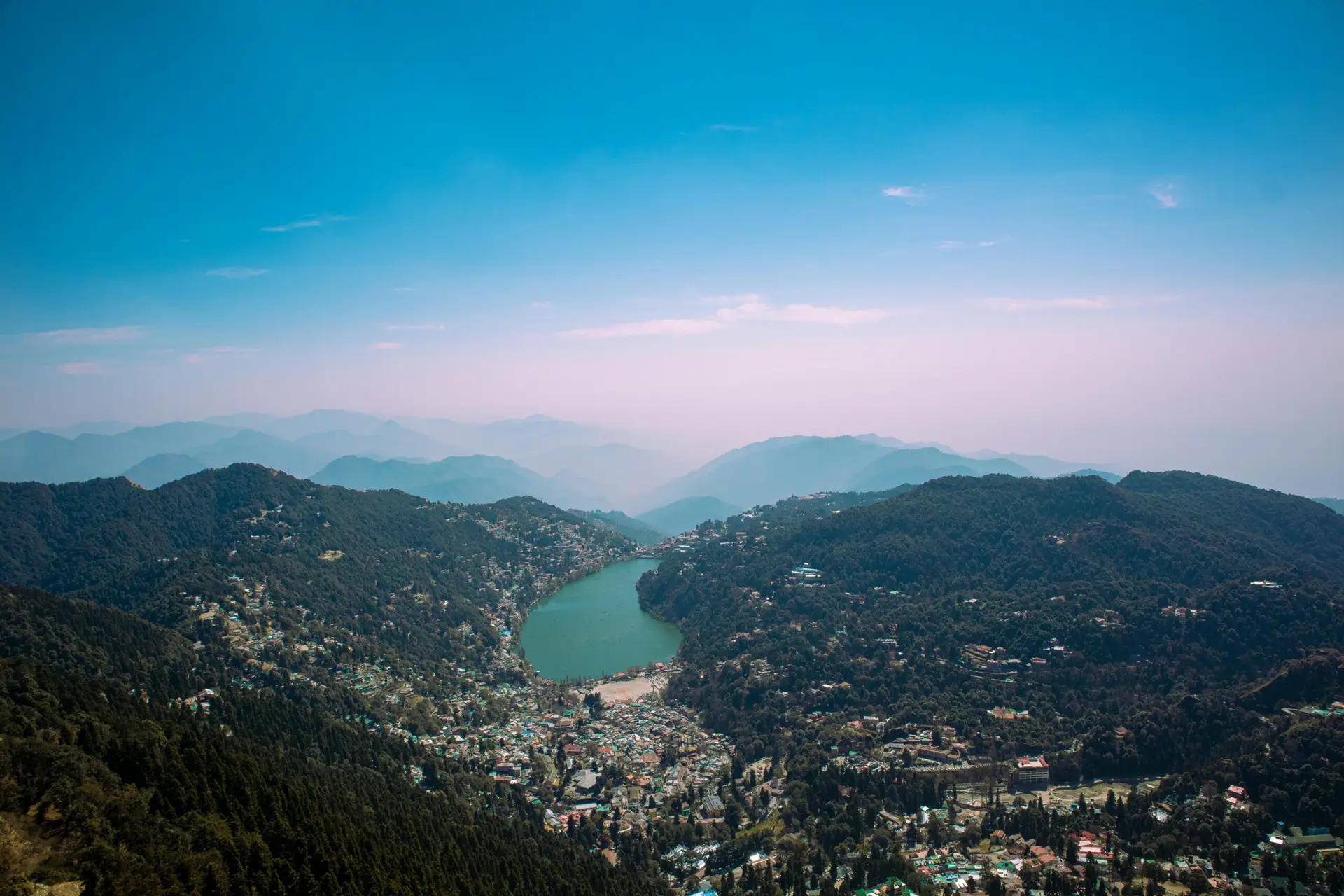 Individuals & Families Aerial shot of Nainital Lake surrounded by lush forests and mountains in India.