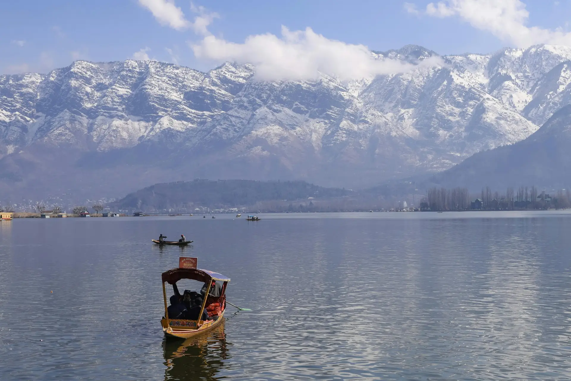 Individuals & Families Peaceful view of Dal Lake in Srinagar surrounded by snowcapped Himalayas, featuring traditional boats.