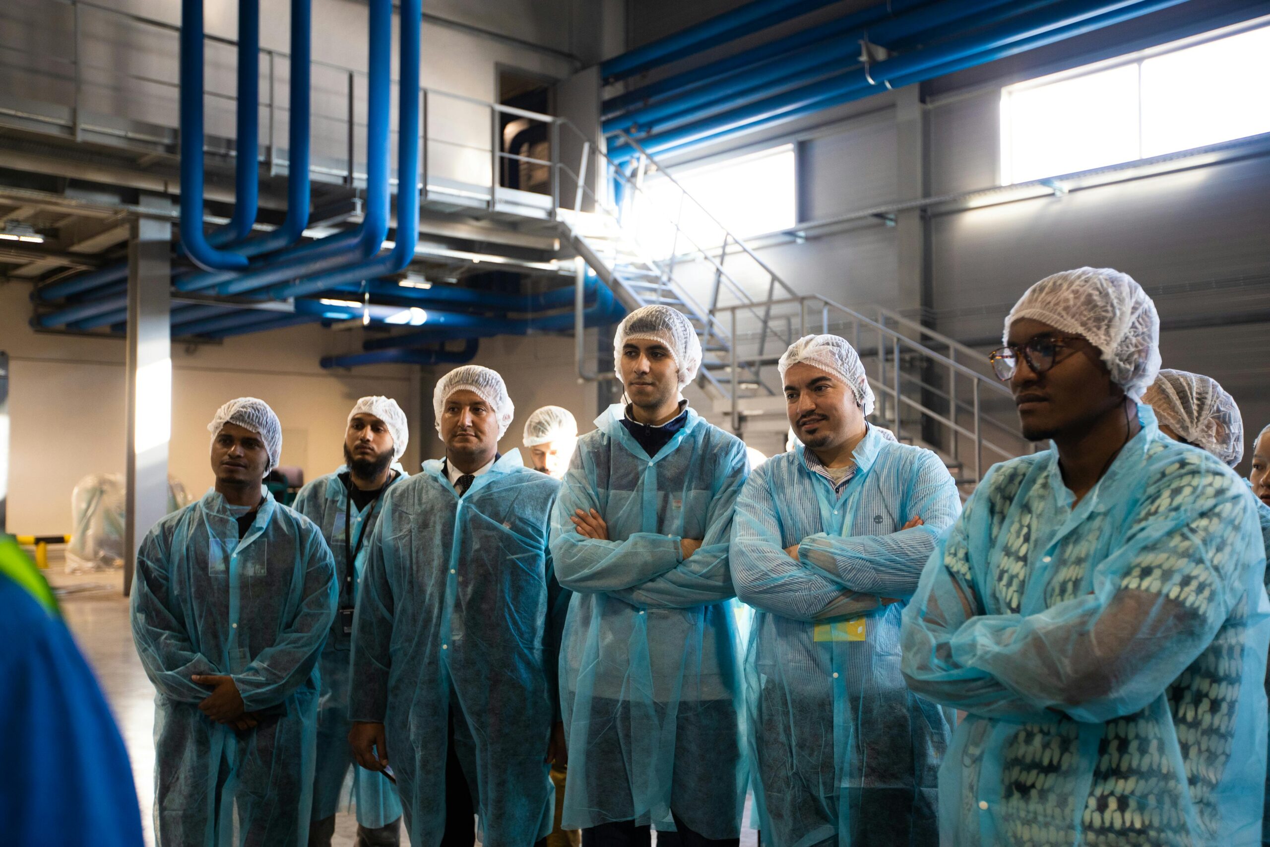 Corporate Travel Group of diverse workers wearing blue protective clothing in an industrial setting.