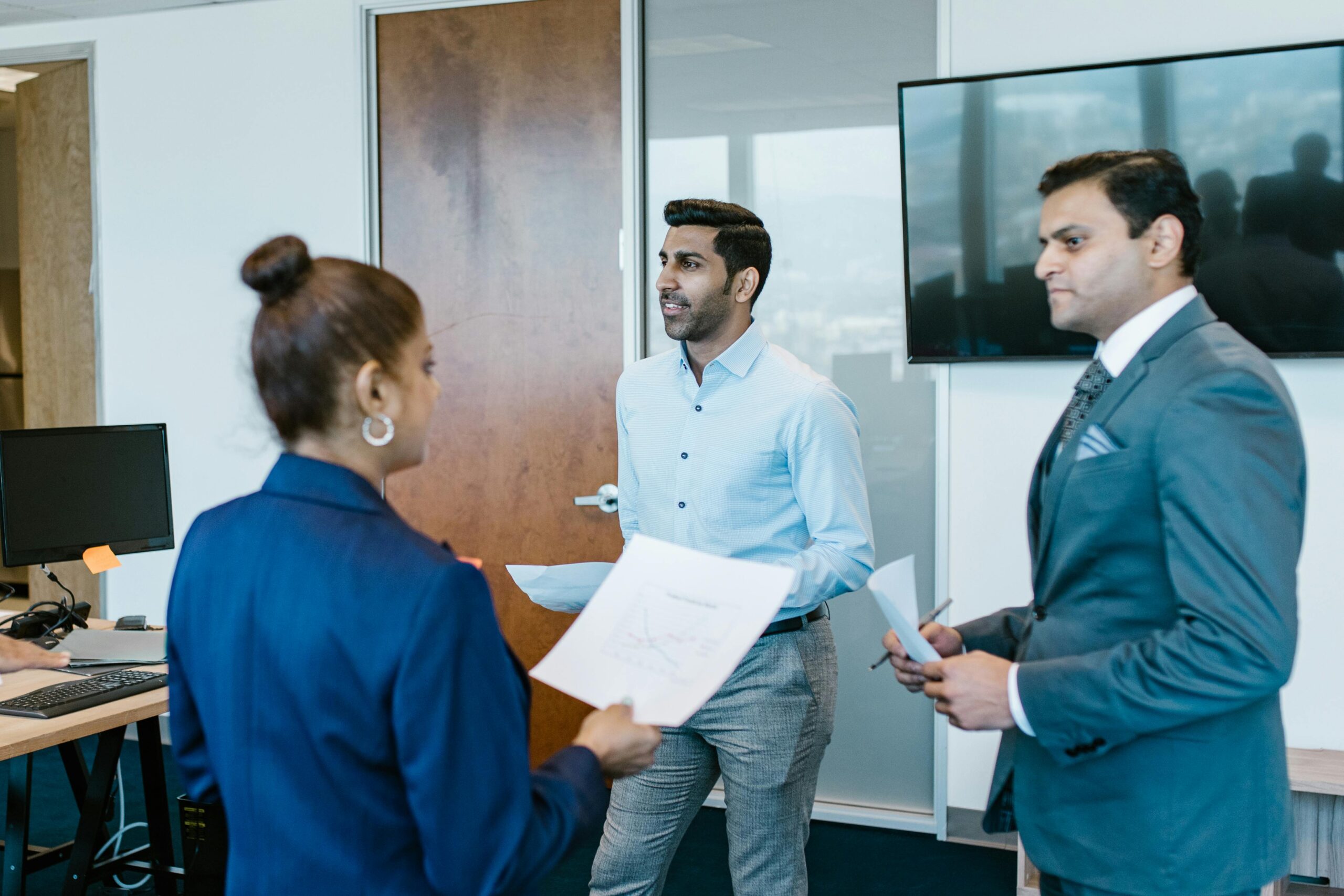 Corporate Travel Professional team in a modern office discussing work documents during a meeting.